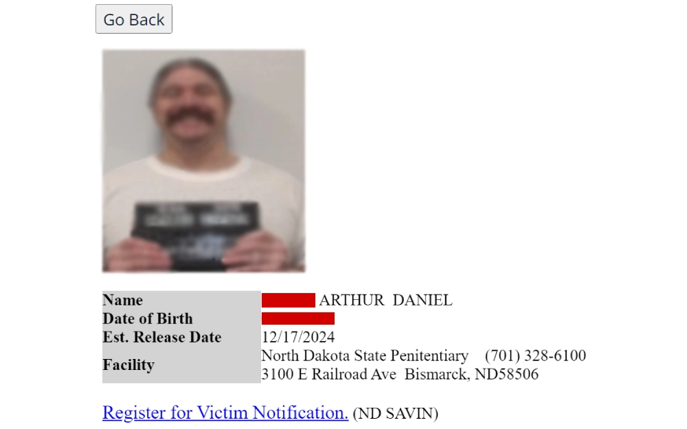 A blurred photograph of an individual holding an identification placard, accompanied by text providing the person's name, date of birth, estimated release date, and the facility location with a contact phone number.